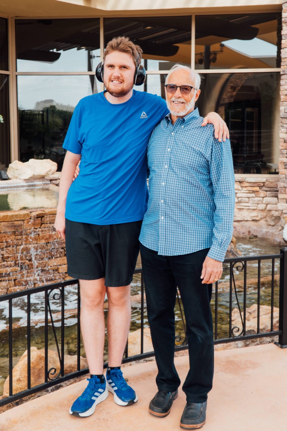 Joe Infranco standing with Cody beside a courtyard fountain.
